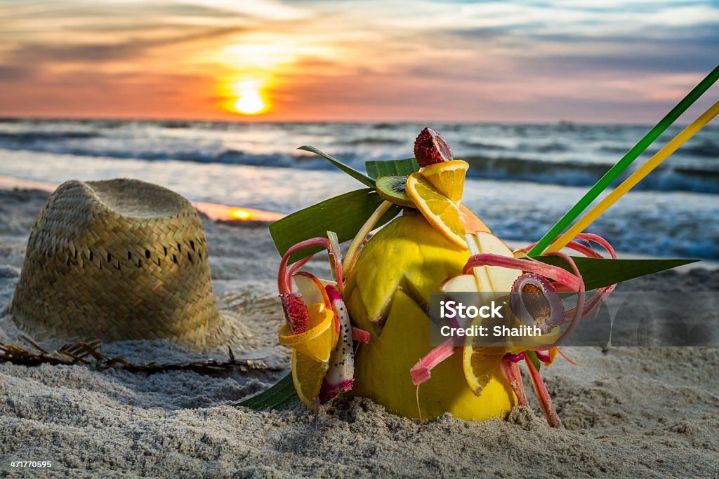 Primo piano di un cocktail di frutta su una spiaggia al tramonto - Foto stock royalty-free di Acqua