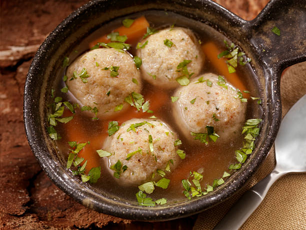 Matzah ball Soup A classic favourite! Fluffy matzo balls floating in roasted chicken and herb broth.- Photographed on Hasselblad H3D2-39mb Camera passover celebration stock pictures, royalty-free photos & images