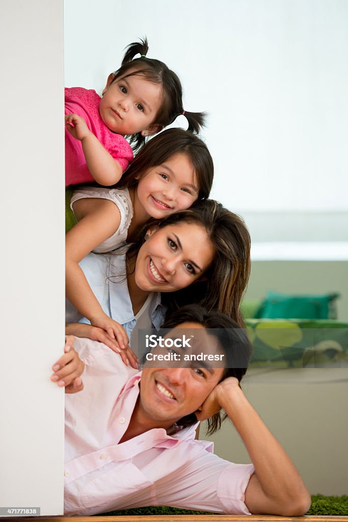 Happy family portrait at home Happy family portrait having fun at home hiding behind a door and lying on the floor Family Stock Photo