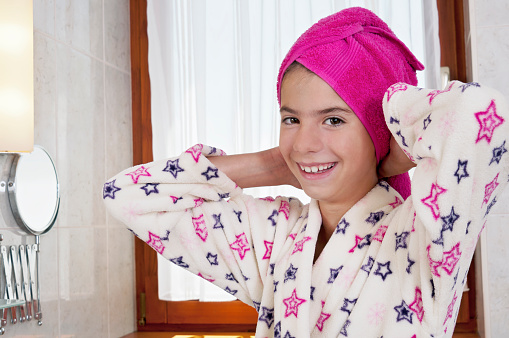 Young woman in bath robe and towel on head in bright bathroom