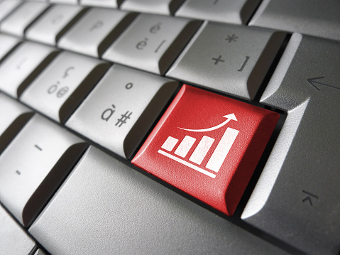 Positive business growth concept with growing bar graph and arrow icon and symbol on a red laptop computer key for Internet and online business.