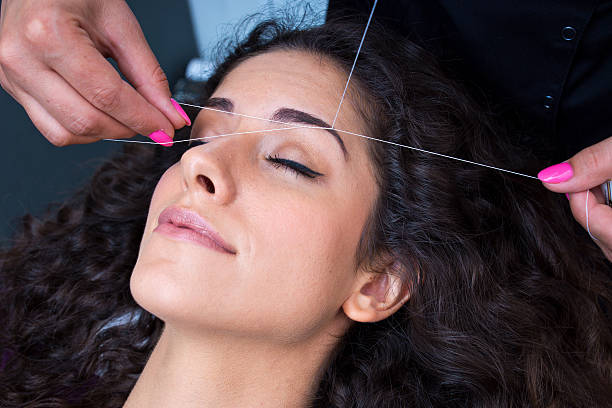 A woman getting her eyebrows threaded stock photo