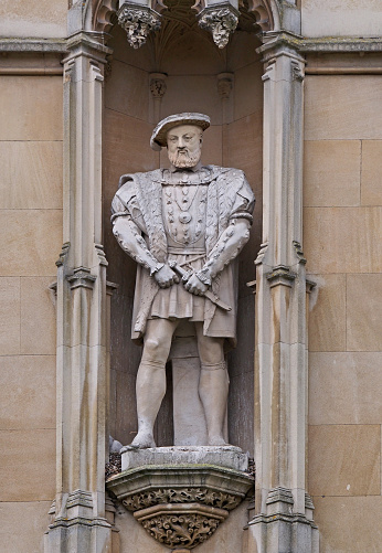statue of King Henry VIII on the outside wall of the building, facing the street