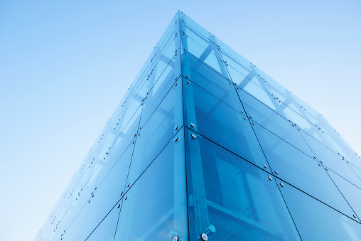 Contemporary office building built in steel and glass. It reflects the blue sky and lens flare occurs. Perspective diminishes as it has been created with a wide angle lens.