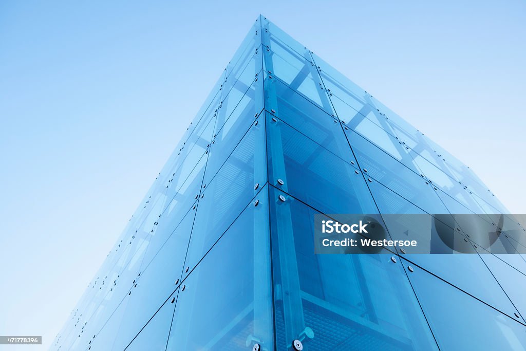 Blue sky over glass and steel office building Contemporary office building built in steel and glass. It reflects the blue sky and lens flare occurs. Perspective diminishes as it has been created with a wide angle lens. Transparent Stock Photo