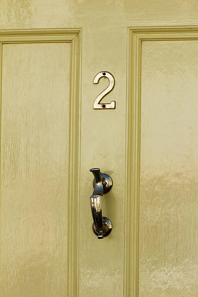 istock Yellow Door with bronze knocker and number 2 471779346