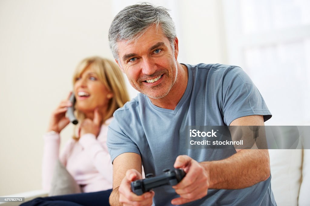 Średnim wieku człowiek, grając w gry wideo w domu - Zbiór zdjęć royalty-free (40-44 lata)
