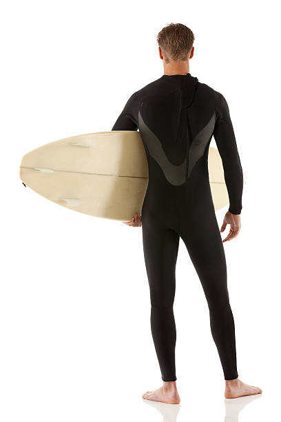 istock Rear view of a surfer standing with surfboard 471784373