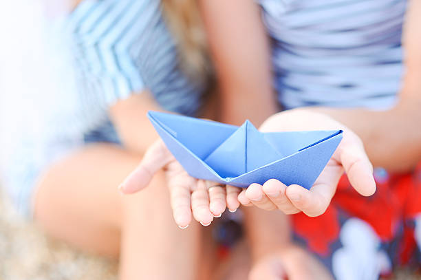 istock Two hands holding paper boat outdoors 471785327