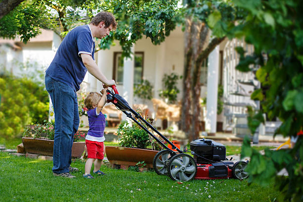 istock Man and little son having fun with lawn mower 471785853