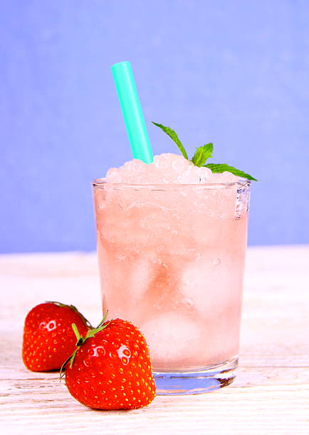 Strawberry slush in glass with straw on blue background, close up