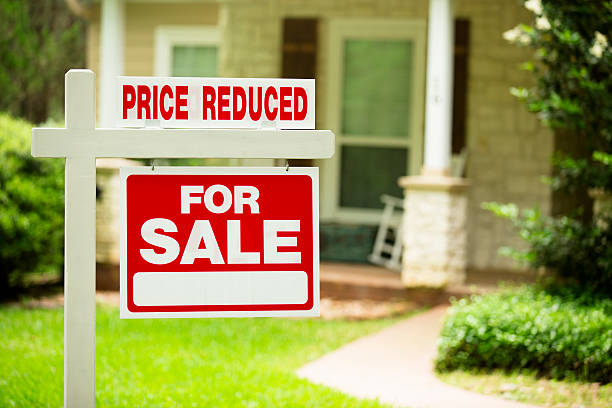 House for sale, price reduced. Real estate sign. Front yard. stock photo