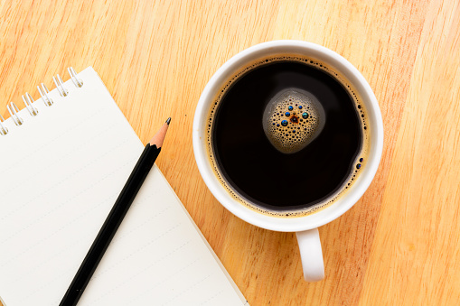 Black coffee and notepad on wooden table