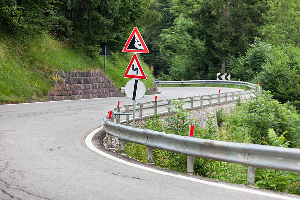 istock Warning traffic sign at metal pole on winding road 471791861