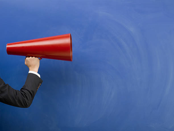 istock Red megaphone in human hand on blue blank blackboard 471792403