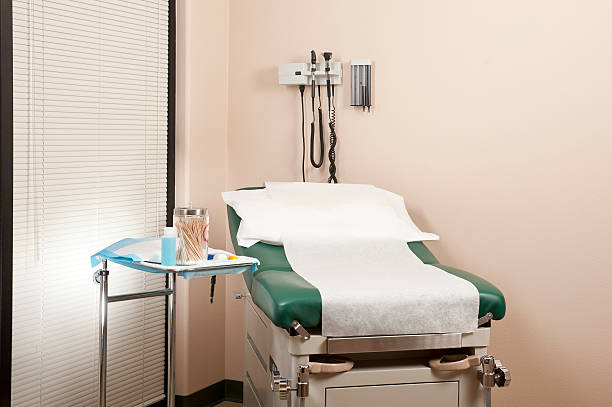 A clean medical exam room with an exam table, soap dispenser, and ears, nose and throat equipment