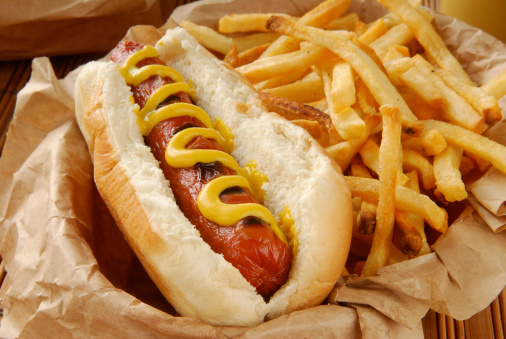 A hot dog with french fries closeup served in a basket