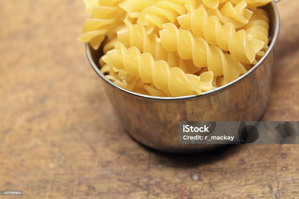 Pasta in measuring cup Measuring cup fill of spiral pasta over wood background Baking Stock Photo
