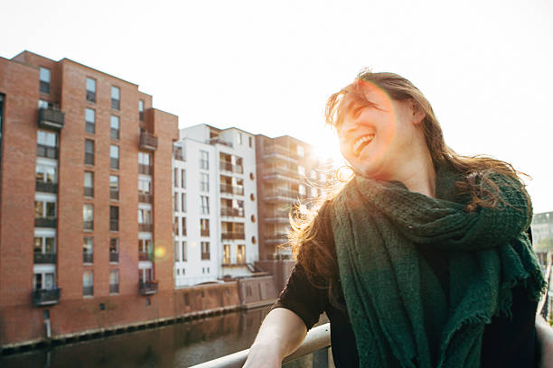 istock city life: laughing woman leans against railing, back lit 471803368