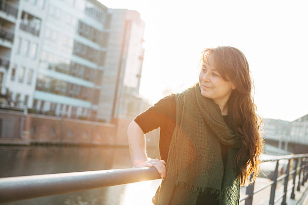 istock city life: woman leans against railing, back lit 471803380