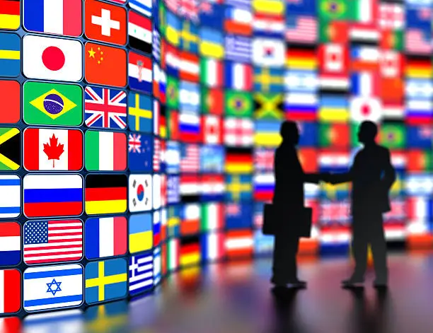 Photo of Businessmen shaking hands in front of the world flags