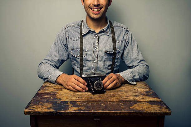 Trendy man with vintage camera at old desk