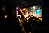 Man driving a private taxi through city streets at night