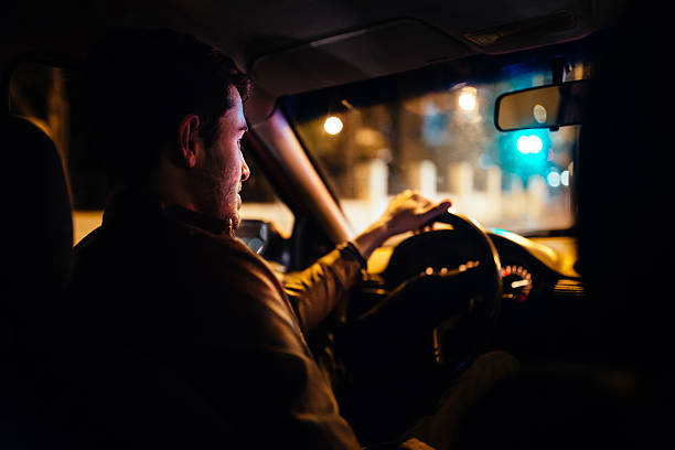 Man driving a private taxi through city streets at night stock photo
