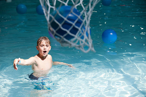 niño jugando al básquetbol en el parque acuático bajo techo - early teens child swimming pool swimming fotografías e imágenes de stock