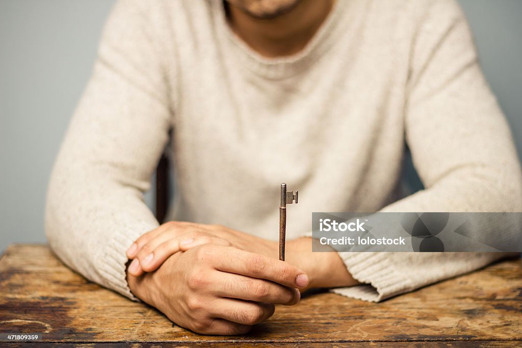 Uomo al tavolo con una chiave - Foto stock royalty-free di Aprire