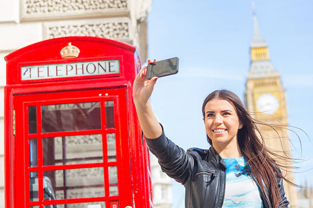 junge frau, die ein selfie in london. - pay phone telephone people women stock-fotos und bilder