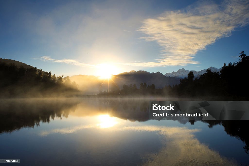 New Zealand Lake At Dawn Dawn on New Zealand's South Island, and the Southern Alps are reflected in the mirror-like surface of Lake Matheson. Beauty In Nature Stock Photo New Zealand Lake At Dawn Dawn on New Zealand's South Island, and the Southern Alps are reflected in the mirror-like surface of Lake Matheson. Beauty In Nature Stock Photo
