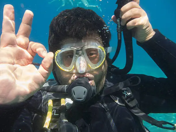 Man diving and showing OK sign with his hand.