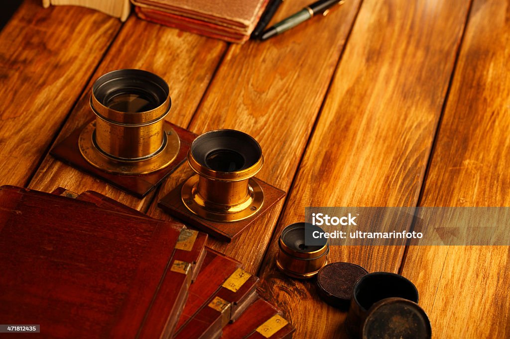 Antique photo equipment Nostalgia. Vintage desk set up. Antique photo equipment, eyeglasses, old photo album, vintage lens,  on wooden table. Aging Process Stock Photo