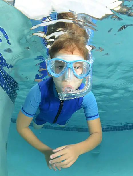 kid swimming underwater in pool in a wetsuit