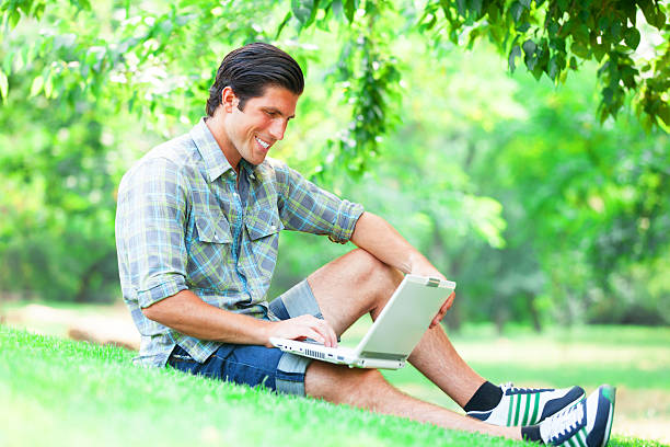 istock Student with laptop at green grass 471814383