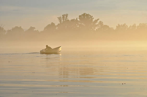 Hombre en el río en la niebla - foto de stock