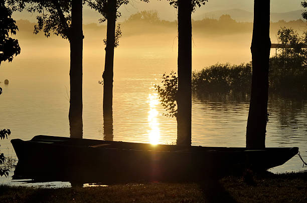 Puesta de sol sobre el río en niebla whit en bote - foto de stock