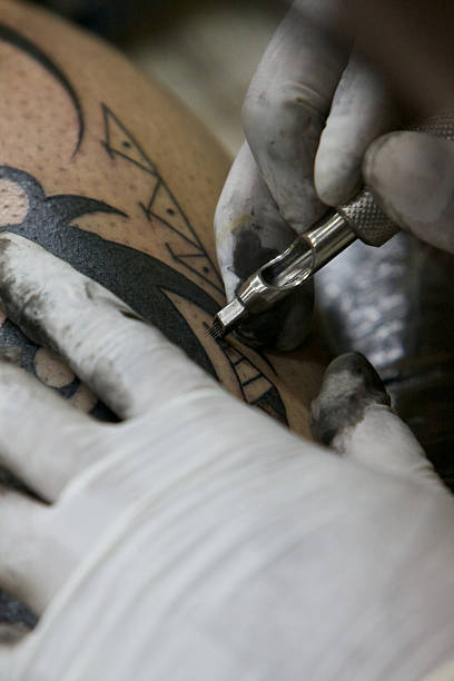 istock tattoo artist tattooing on a somebody leg 471816683