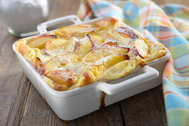 Peach clafoutis Peach clafoutis in a baking dish on a rustic table clafoutis stock pictures, royalty-free photos & images