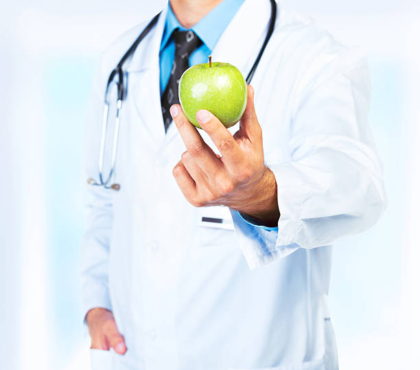istock Doctor's hand holding a fresh green apple close-up 471820657
