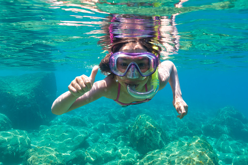 a little girl with mask exploring underwater in the Mediterranean Sea