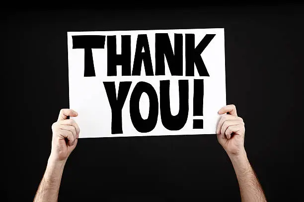 Man holding poster with thank you in front of a black background