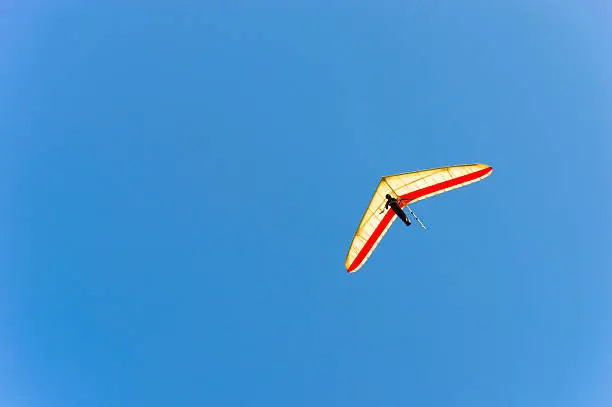Hang Glider navigating in clear blue sky 