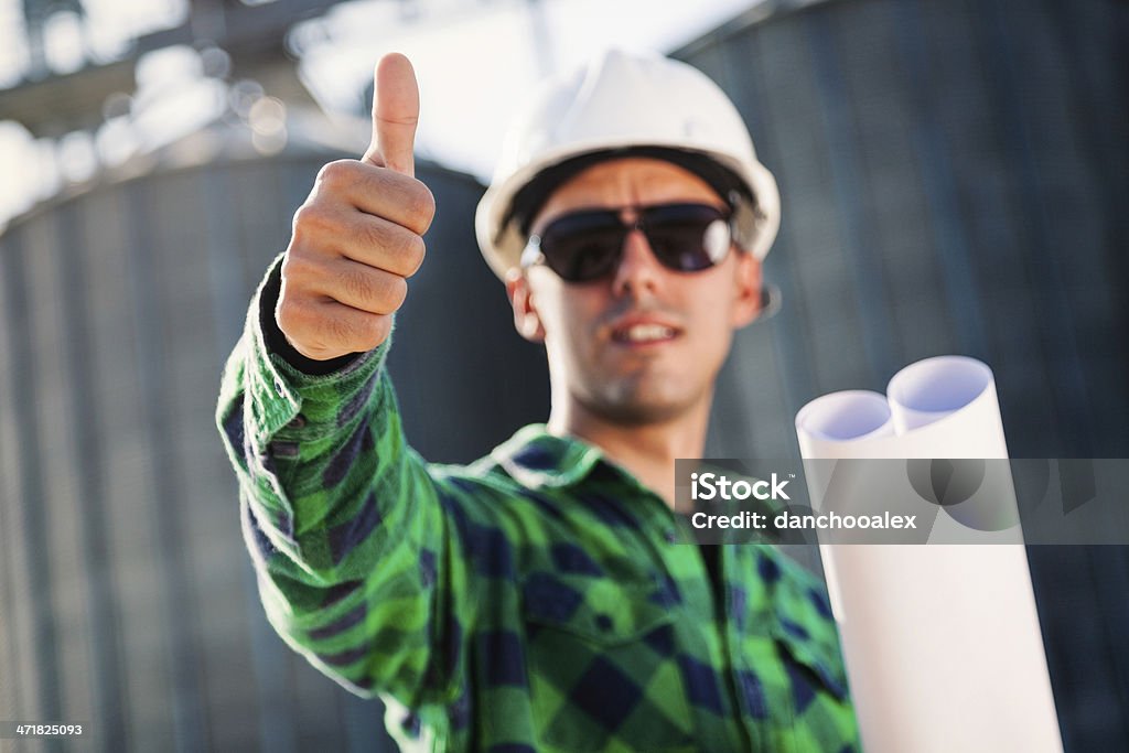 Construcción trabajador sonriente mostrando pulgar hacia arriba y - Foto de stock de Accesorio de cabeza libre de derechos