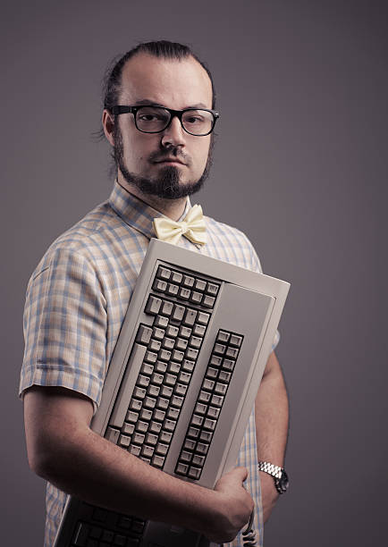 Computer geek Funny guy posing with a keyboard on grey background nerd stock pictures, royalty-free photos & images
