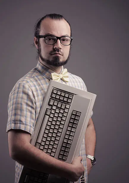 Funny guy posing with a keyboard on grey background