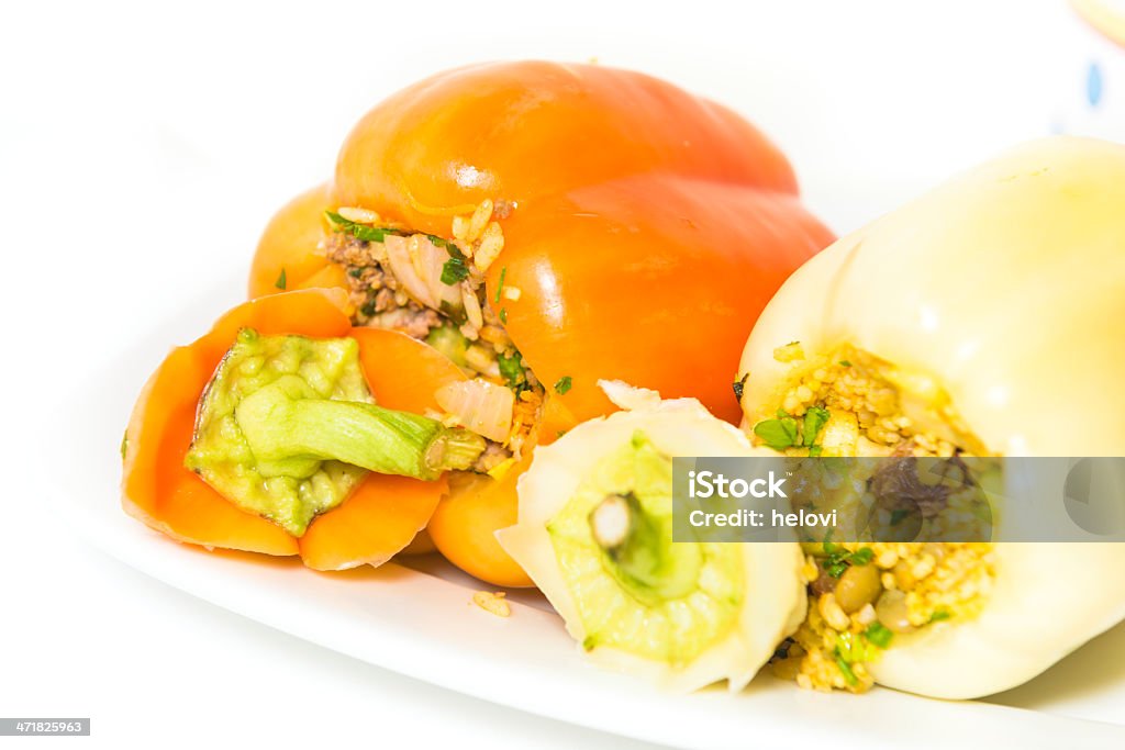 Stuffed peppers Two stuffed peppers, one orange with minced meat and rice, yellow one with vegetables and grain. White background. Balkans Stock Photo