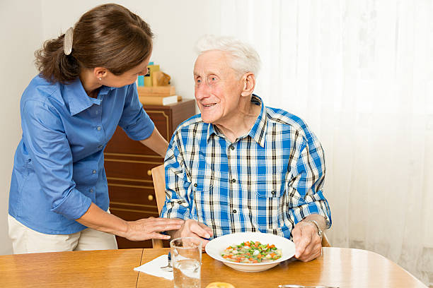 istock Home caregiver giving senior man lunch 471826109