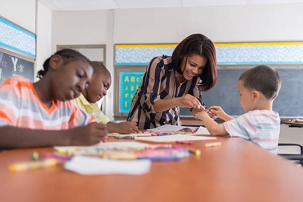 Woman helping a student at art in an inner city school Multi-racial inner city school students in special education classroom working on an assignment with the teacher. special education stock pictures, royalty-free photos & images